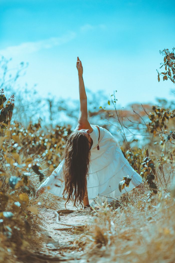 The Art of Drawing Readers In: Your attractive post title goes here A woman practicing yoga in a peaceful, sunny outdoor setting surrounded by foliage.